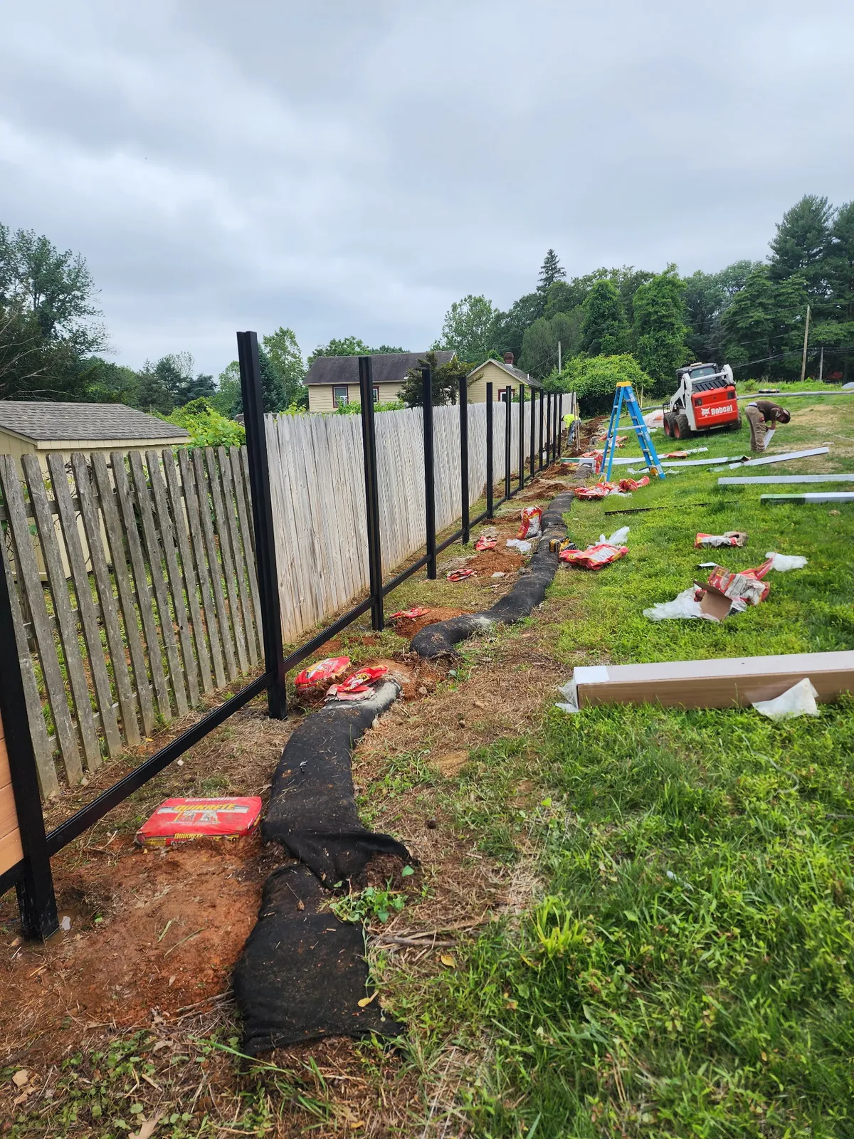 Black aluminum fence posts being installed with equipment on site
