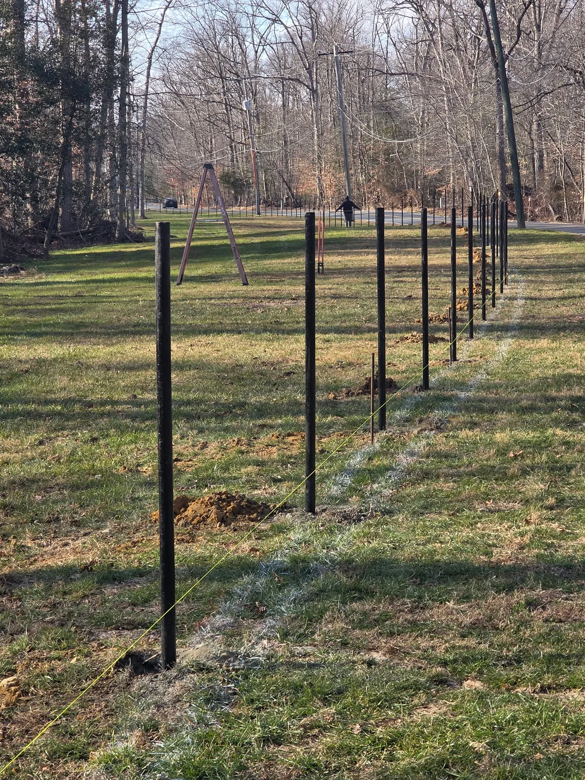 Metal fence posts being set for chain link fence installation